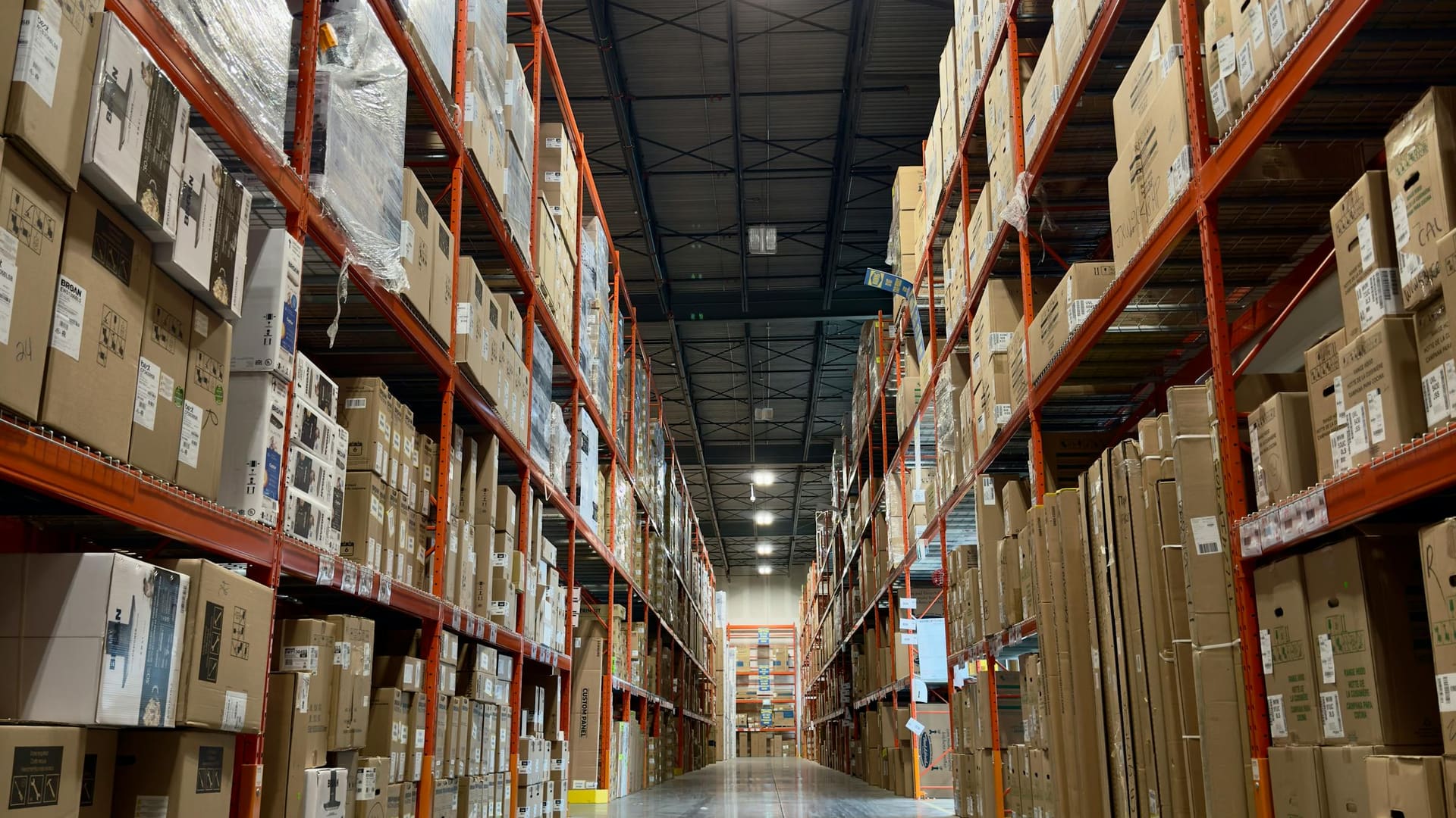 A loaded orange pallet racking aisle receding to a vanishing point